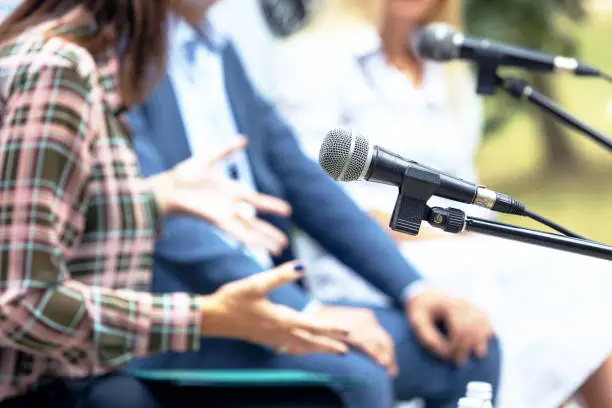 Microphone in focus against blurred people at round table event or business conference