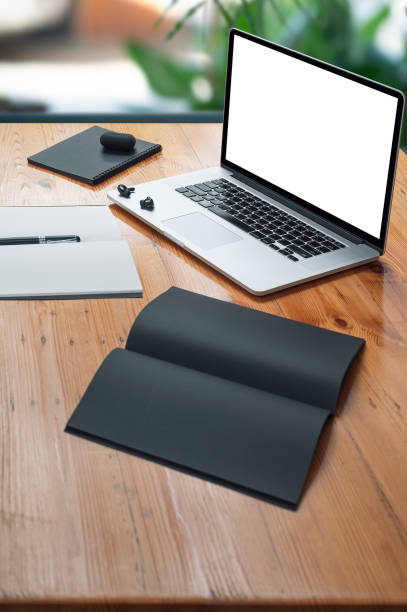 istock Mockup blank screen laptop computer and supplies on wooden table, vertical view. 1345802391