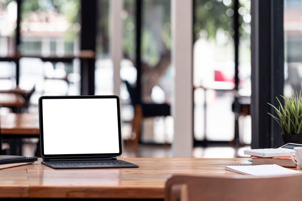 istock Mockup tablet with magic keyboard and supplies on wooden table in co-workspace. 1345802434