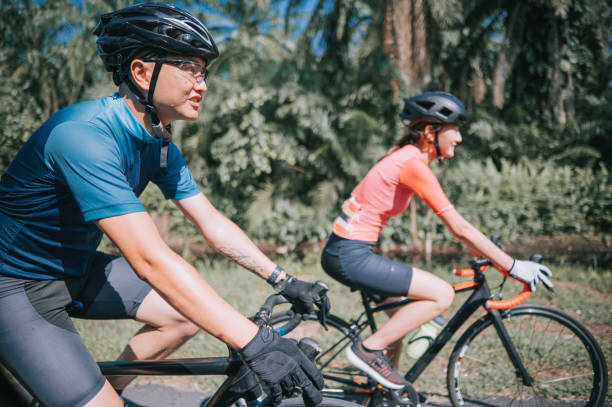 seitenansicht asiatisches chinesisches paar radfahrer genießen rennradfahren während des wochenendmorgens zusammen ländliche szene - cyclist cycling road women stock-fotos und bilder