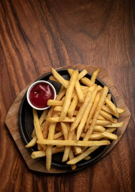 portion of french fries potato snack on wood table background with ketchup in restaurant