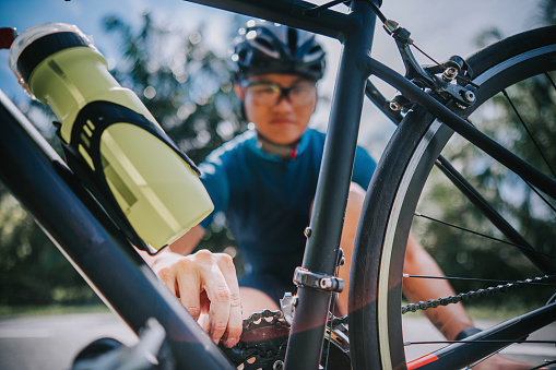 Asian chinese male Cyclist fixing road bike chain at road side of rural scene