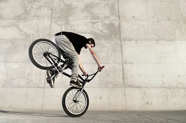 Young BMX bicycle rider on a grey urban concrete background