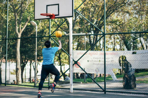 istock Handsome man playing basketball at public park 1345805601