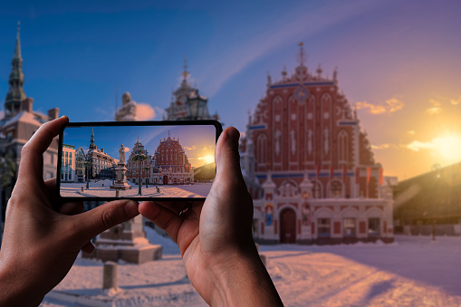 Tourist taking photo of Town Hall Square during sunset in winter in Riga, Latvia