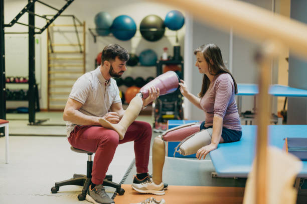 Physiotherapist helping young woman with prosthetic legs stock photo