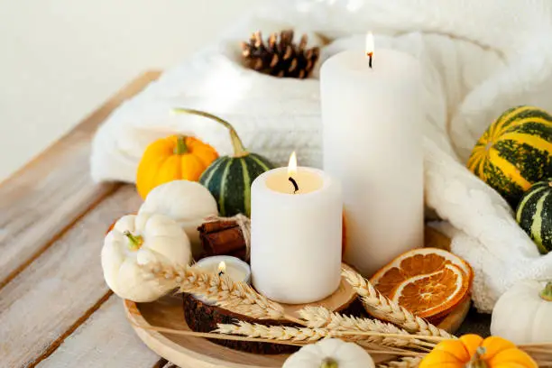 Photo of Pumpkins and candle on a wooden table. Autumn season image, cozy home atmosphere. Thanksgiving or Halloween zero waste table decor. Close up