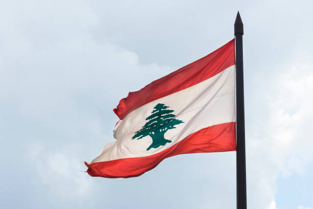 zerrissene libanesische flagge vor bewölktem himmel - lebanese flag stock-fotos und bilder