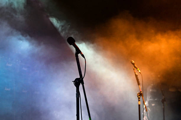istock Microphones in silhouette with coloured spotlights 1345808646