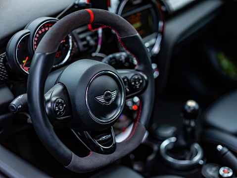 Toronto, Ontario, Canada- October 09, 2021. Driver's side interior of Volcanic orange colour MINI COOPER parked on city street in East end of Toronto, Canada. Neighbourhood known as The Beaches, near Lake Ontario shore. This is the third generation model F55 (4 doors), since BMW took over iconic brand of MINI. For the first time, this compact car features engine build and designed by BMW, and packs even more power and torque than previous models since 2002 to present. Original design clues and themes are still present on this brand new model. Mini has been around since 1959 and has been owned and issued by various car manufacturers.