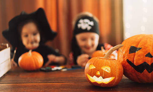 Pumpkins with carved faces on the background of children in costumes.