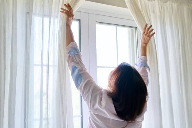 istock Close-up of woman's hand opening and closing light translucent curtains 1345820379