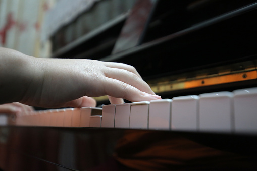 An Asian teenage girl is learning piano through online system.