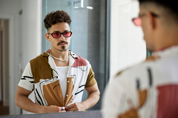Mid Adult Man Buttoning Shirt in Bathroom Mirror