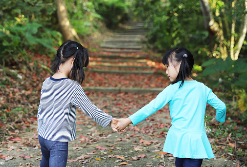 Asian girls playing tung blossom and dead leaves in forest.