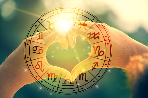Las manos de mujeres y hombres tienen la forma del corazón con la luz del sol que pasa a través de las manos tienen símbolos astrológicos photo