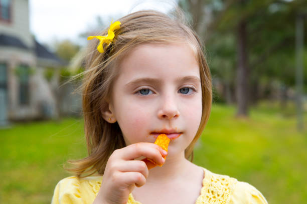 istock Blond kid girl eating corn snacks in outdoor park 1345831448