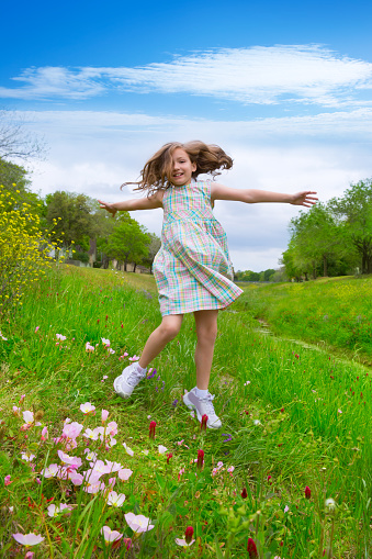 happy children girl jumping on spring poppy flowers meadow with motion blur