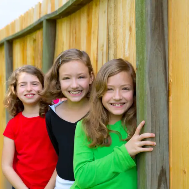 Girls group in a row smiling in a wooden fence outdoor