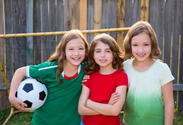 three sister girls friends soccer football winner players on the backyard