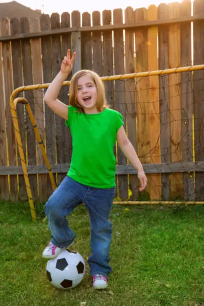 Blond little girl soccer player happy in backyard with ball