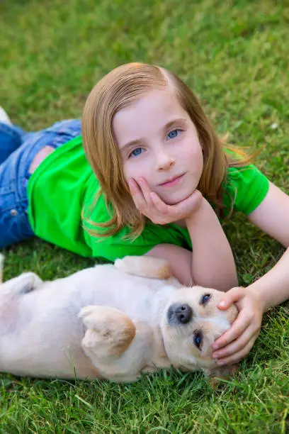 Blond happy girl with her chihuahua doggy portrait lying on lawn