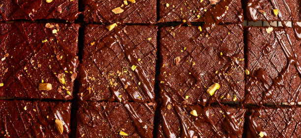 istock Chocolate squares with pistachio nuts and strawberries on white paper on a light background, top view, horizontal composition. Banner. 1345835658
