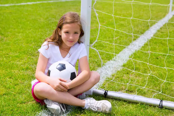 Soccer football kid girl relaxed on grass lawn with ball