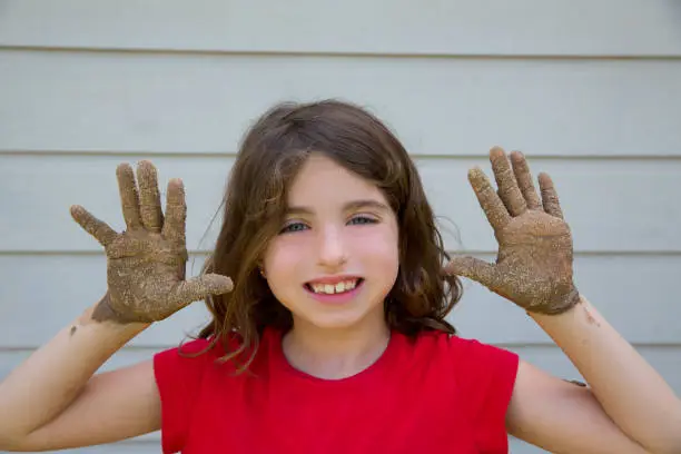 happy kid girl playing with mud with dirty hands smiling portrait