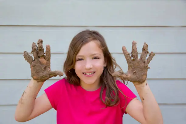 happy kid girl playing with mud with dirty hands smiling portrait