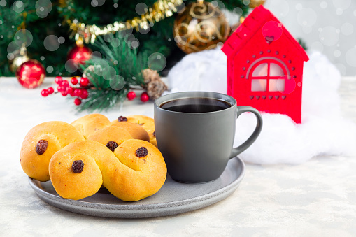 Swedish and scandinavian Christmas saffron buns Lussekatter with cup of coffee, Christmas decoration on a background, horizontal