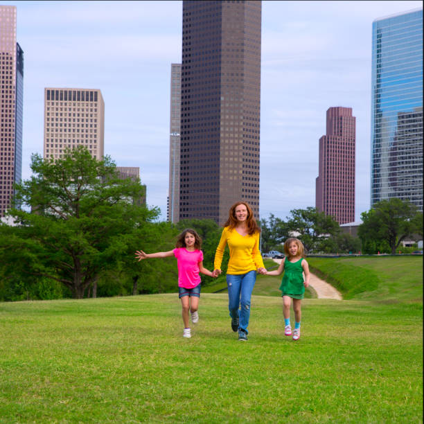 istock Mother and daughters walking holding hands on city skyline 1345837250