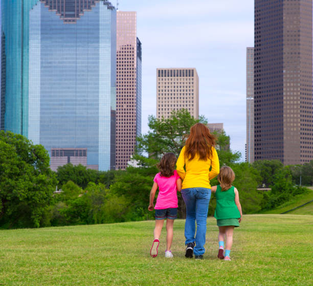 istock Mother and daughters walking holding hands on city skyline 1345837282