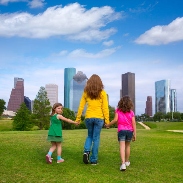 istock Mother and daughters walking holding hands on city skyline 1345837373
