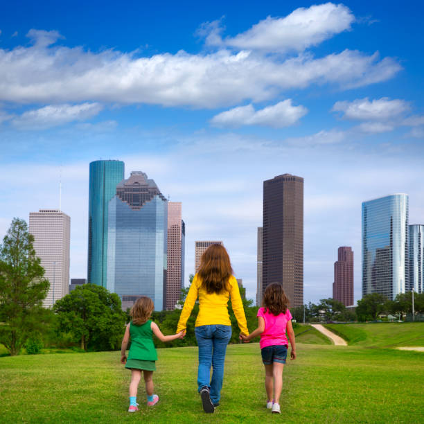 istock Mother and daughters walking holding hands on city skyline 1345837403