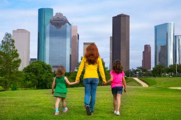 istock Mother and daughters walking holding hands on city skyline 1345837923