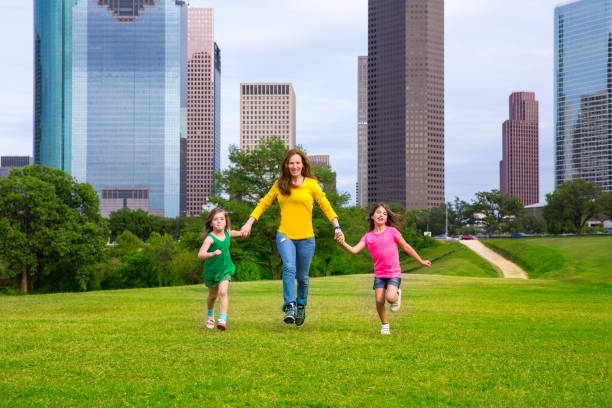 istock Mother and daughters walking holding hands on city skyline 1345837970