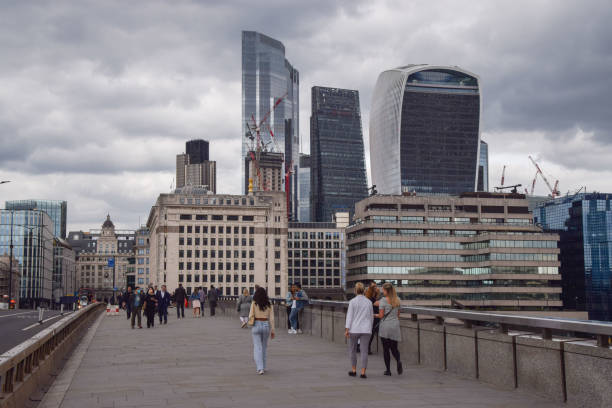 London Bridge and City of London, UK London, United Kingdom - September 17 2021: people walk along London Bridge with a view of the City of London skyline on an overcast day. waterloo bridge stock pictures, royalty-free photos & images