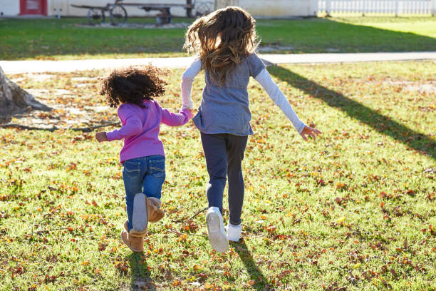 niñas multiétnicas jugando a correr en el parque - family grass toddler african descent fotografías e imágenes de stock