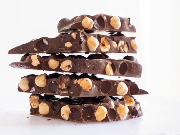 istock Stack of chocolate. Dark chocolate with whole hazelnuts on white background. Pile of dark chocolate with nuts. 1345845216