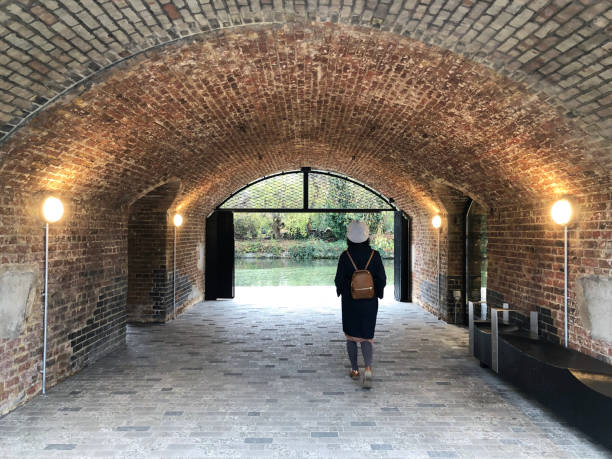 rear view of woman walking below arch. - women rear view one person arch imagens e fotografias de stock