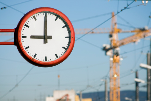 The clock strikes 9AM as the work day begins near a construction site. Photo has shallow DOF, with main focus on the clock.