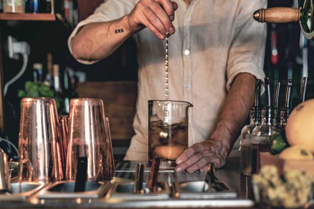 istock An expert bartender mixing a cocktail in a glass mixer with a long spoon, 1345849320