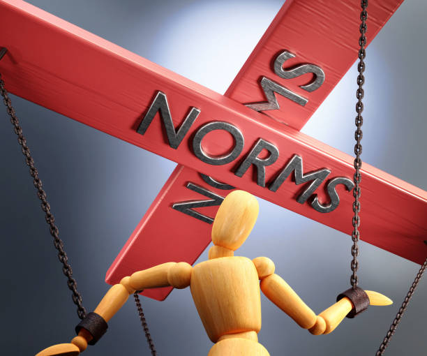 istock Norms control, power, authority and manipulation symbolized by control bar with word Norms pulling the strings (chains) of a wooden puppet, 3d illustration 1345850731