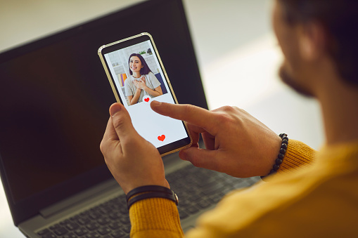 single man looking at pretty young womans photo on dating app and pressing like button