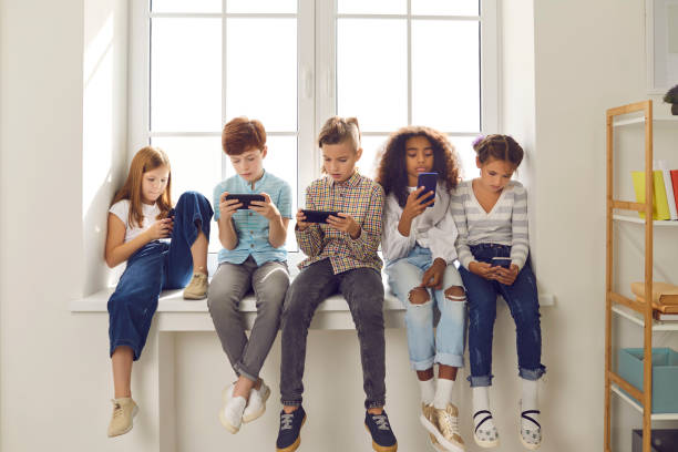 children of different nationalities play online games or read social networks on mobile phones. - pre adolescent child imagens e fotografias de stock