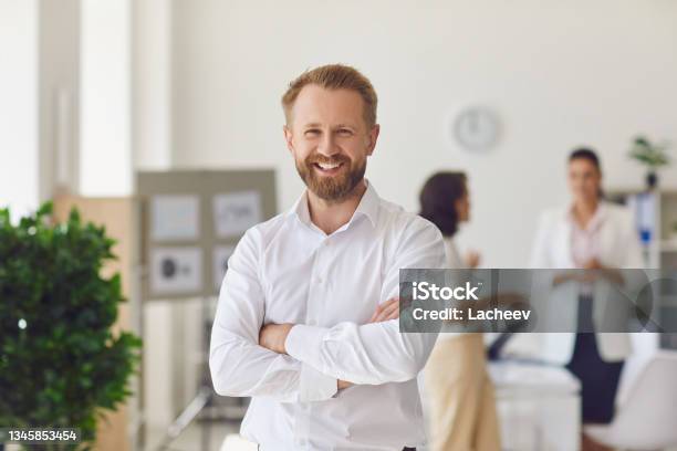 Happy Successful Businessman Or Company Employee Standing In Office Looking At Camera Stock Photo - Download Image Now