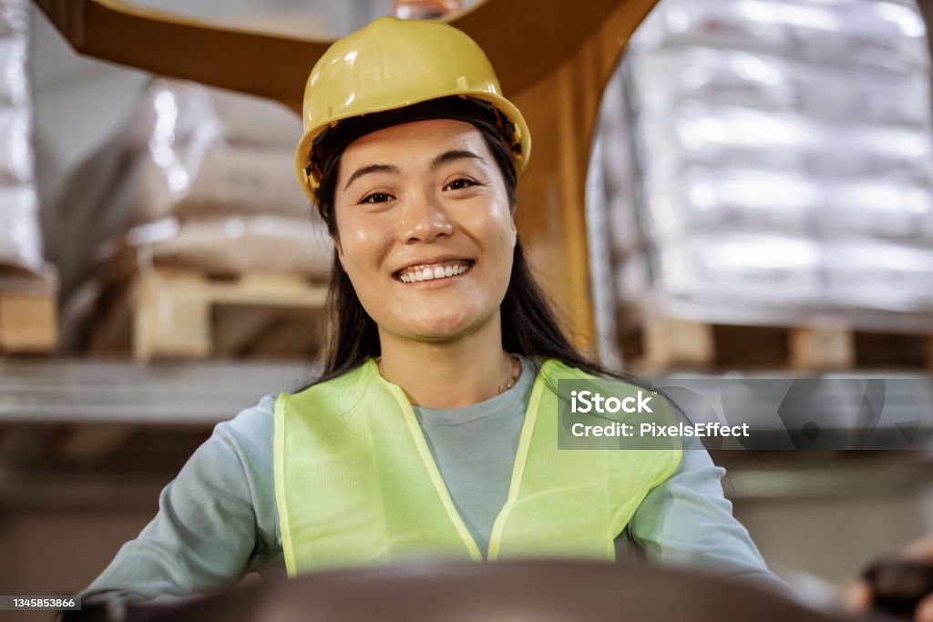 Let’s get things moving Attractive Asian workwoman sitting in forklift loader and smiling at the camera. Industrial and industrial workers concept 25-29 Years Stock Photo