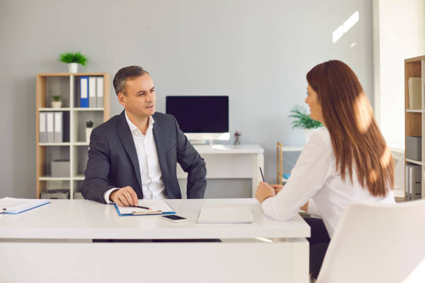 istock Male and female office workers sitting at a desk and discussing office workflows. 1345854853