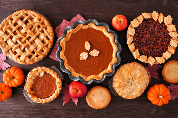 Assortment of homemade fall pies, table scene on dark wood Assortment of homemade fall pies. Apple, pumpkin and pecan. Top down view table scene on a dark wood background. sweet pie stock pictures, royalty-free photos & images